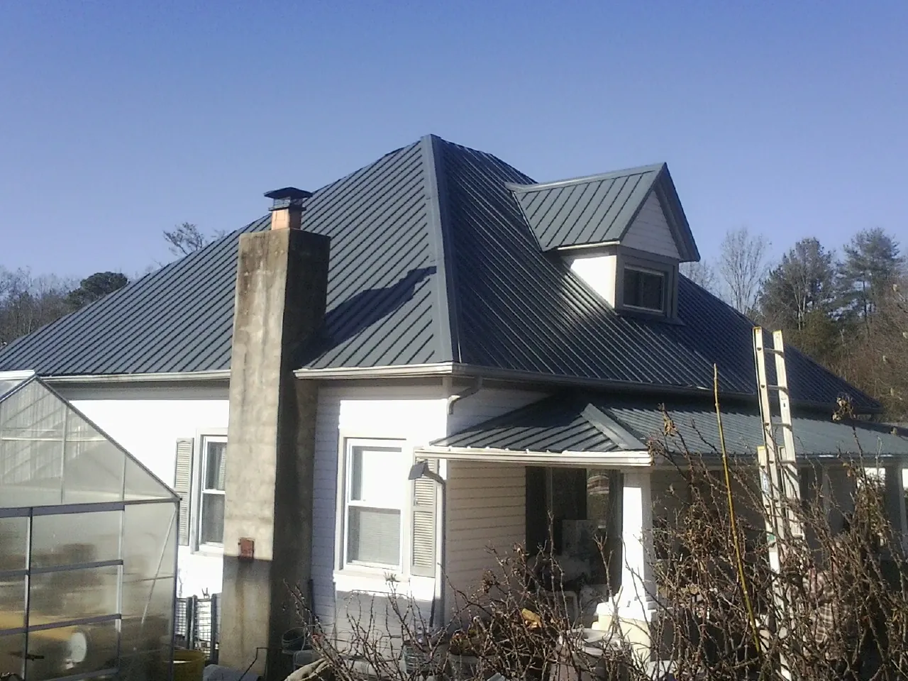 Dark blue standing seam metal roof on a white farmhouse with dormer — Slate & Tile Roof Repair by Roofing Brothers in Moultonborough