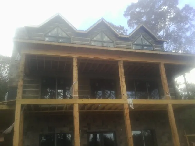 Dormers and porch framing on a large log home under construction — Roof Coating work by our crew in Moultonborough