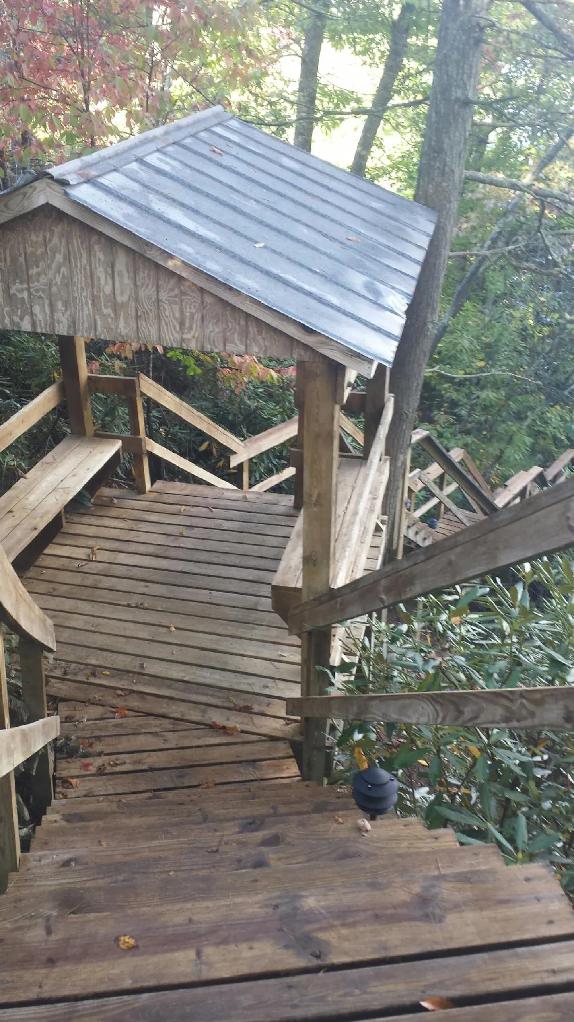 Metal roofed shelter over wooden steps on a wooded walkway — Skylight Repair & Installation work by our crew in Moultonborough