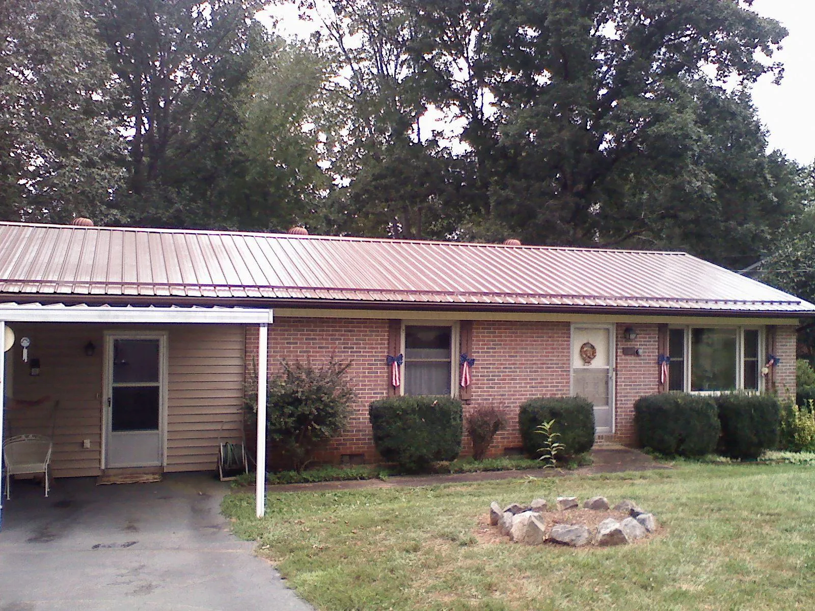 Bronze metal roof and carport on a brick ranch home — Roof Repair work by our crew in Moultonborough