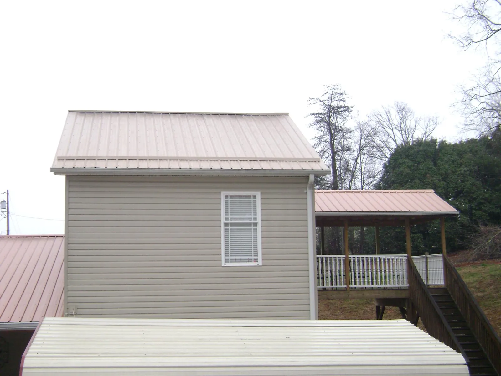 Tan metal roofs on a two story addition and attached porch, from a Roof Replacement job in Moultonborough
